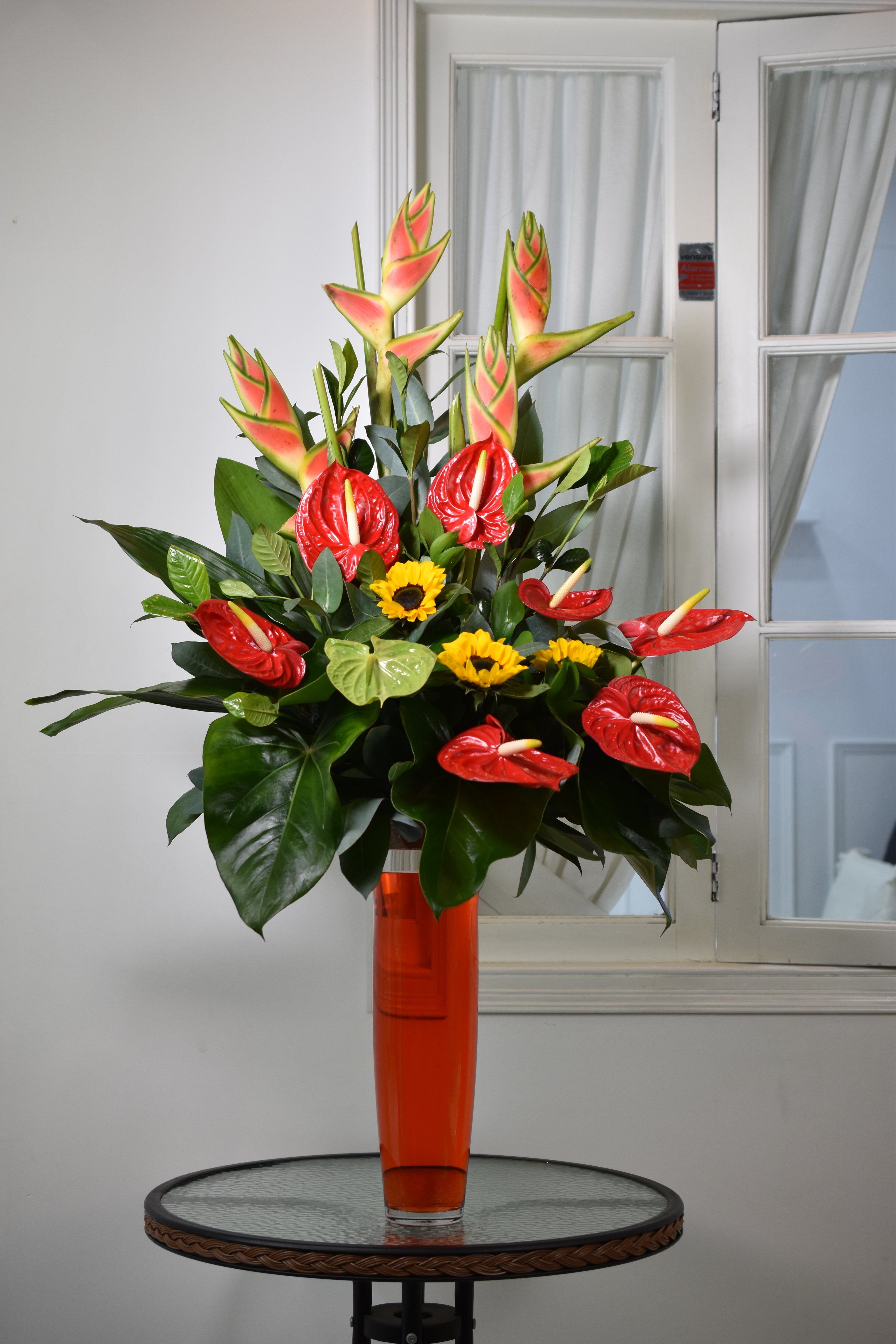 Arreglo floral de ANturios, girasoles y Heliconias